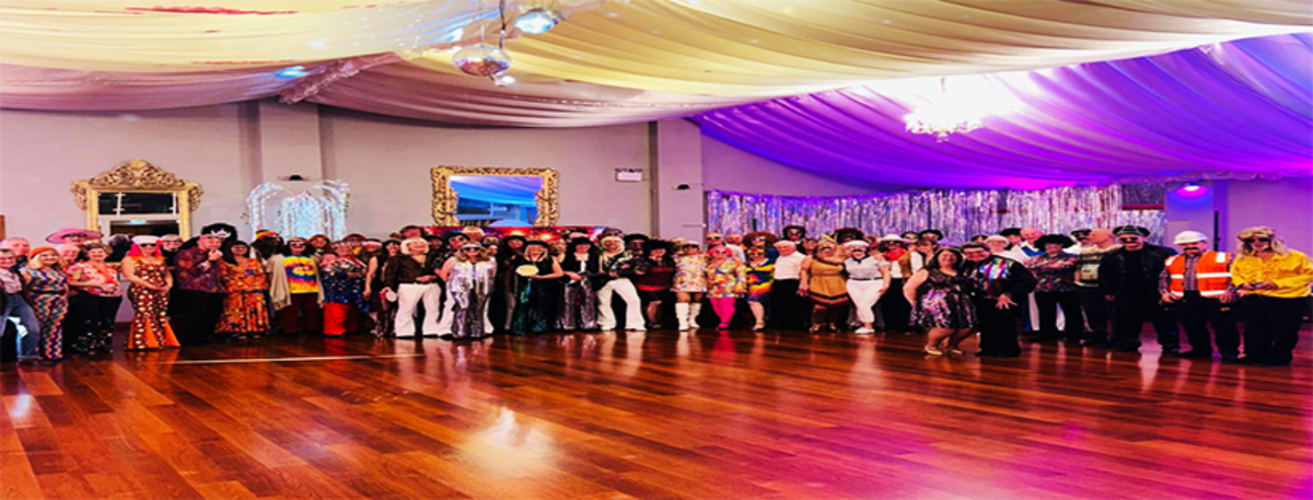 A multi‑age group of dancers smiling on stage during a lively performance